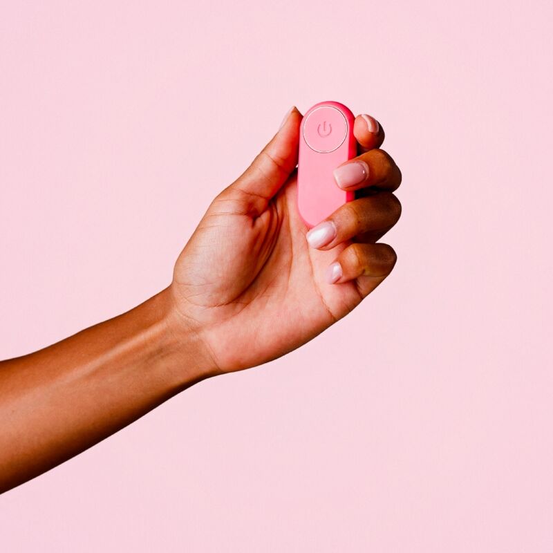 Main tenant la télécommande corail du vibromasseur de culotte ILY Panty Vibe